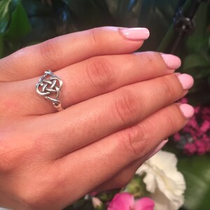 May include: A silver ring with a Celtic knot design in the shape of a heart.
