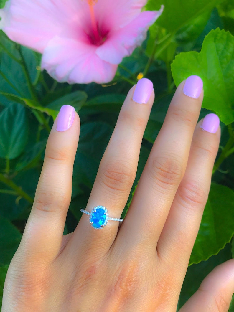May include: A silver ring with a blue oval gemstone surrounded by smaller clear gemstones.