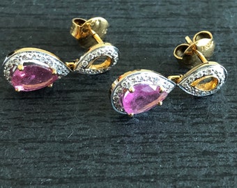 May include: A pair of gold earrings featuring pink pear-shaped gemstones set within a halo of small diamonds.
