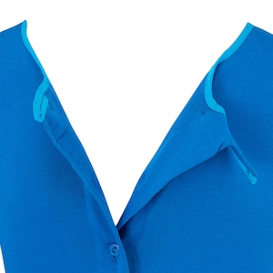 May include: Close-up of a bright blue button-down shirt. The shirt has a V-neck design with a contrasting light blue trim along the collar and button placket. The fabric appears smooth and lightweight, with a single button visible.