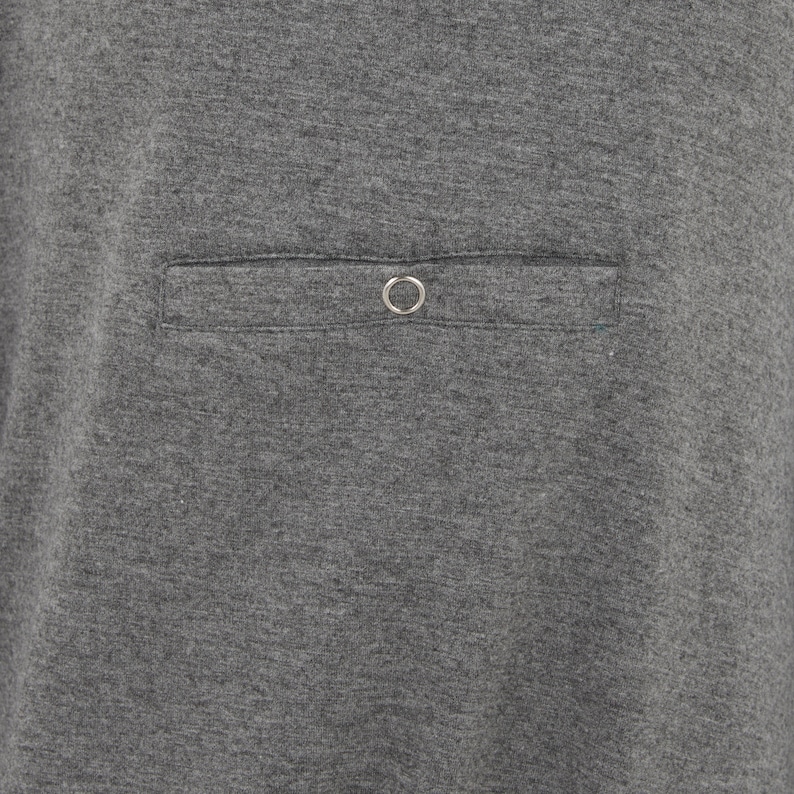 May include: A gray t-shirt with a single pocket on the front. The pocket has a metal ring on the top.