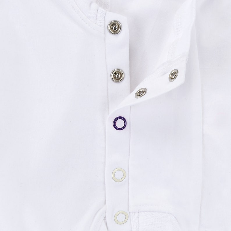 May include: White baby onesie with a row of silver snaps down the front.