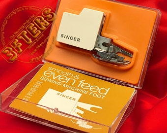 May include: A white Singer sewing machine foot in a clear plastic case with a yellow and orange label that reads "smooth & even feed sewing machine foot".