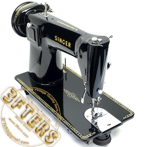 Puede incluir: M&aacute;quina de coser Singer negra vintage con letras y detalles dorados. La m&aacute;quina tiene una superficie brillante y se asienta sobre una base negra con un borde dorado decorativo. La palabra "SINGER" es claramente visible.
