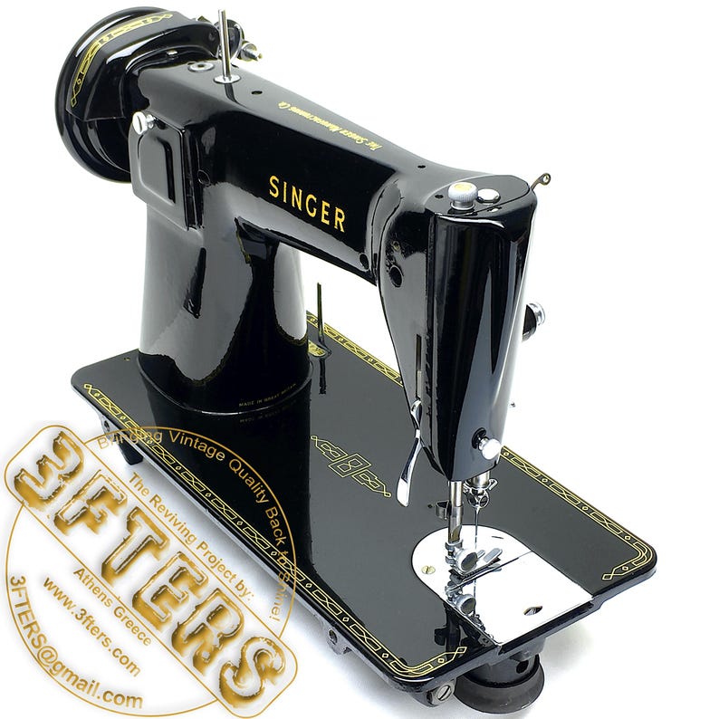 Puede incluir: M&aacute;quina de coser Singer negra vintage con letras y detalles dorados. La m&aacute;quina tiene una superficie brillante y se asienta sobre una base negra con un borde dorado decorativo. La palabra "SINGER" es claramente visible.