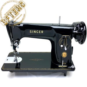 Puede incluir: Una m&aacute;quina de coser Singer negra vintage con letras y detalles dorados. La m&aacute;quina tiene una base negra con un dise&ntilde;o dorado, una aguja plateada y un gran volante. La palabra "SINGER" se muestra de forma destacada.
