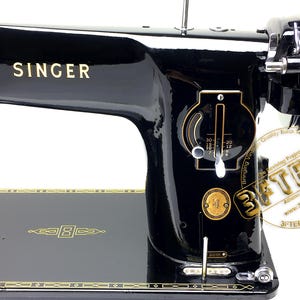 Puede incluir: Una m&aacute;quina de coser Singer negra vintage con detalles dorados. La m&aacute;quina presenta el logotipo de Singer en dorado, un dial numerado y adornos dorados. El n&uacute;mero de modelo 201K es visible.