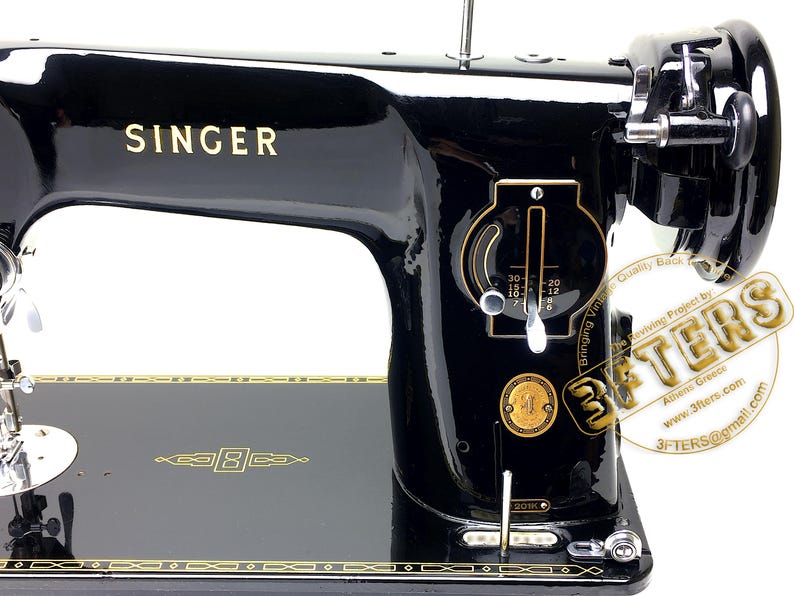Puede incluir: Una m&aacute;quina de coser Singer negra vintage con detalles dorados. La m&aacute;quina presenta el logotipo de Singer en dorado, un dial numerado y adornos dorados. El n&uacute;mero de modelo 201K es visible.