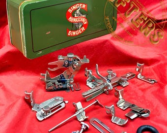 May include: A rectangular green metal Singer sewing machine accessory tin featuring a red logo with a person operating a machine. Included are various silver-toned metal sewing machine presser feet, attachments, a metal screw, and a black rubber ring.