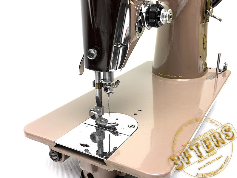 May include: A vintage sewing machine with a brown and beige color scheme. The machine features a shiny chrome needle and a beige base. The machine has a classic design, with a focus on functionality and durability. The machine is likely used for sewing and crafting.