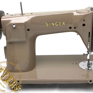 May include: A vintage Singer sewing machine in a beige color, with the brand name in gold lettering. The machine has a dark brown flywheel and a silver needle and presser foot. The machine is on a white background.
