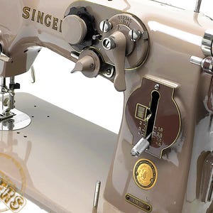 Puede incluir: Primer plano de una máquina de coser Singer vintage en color beige neutro. La máquina presenta varios diales, palancas y una placa de aguja. El logotipo de Singer es visible en el cuerpo de la máquina. Un ejemplo clásico de equipo de costura.