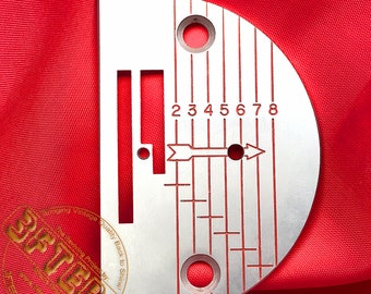 May include: A silver sewing machine foot with a red scale marked 2, 3, 4, 5, 6, 7, and 8. The foot has a slot for a needle and a small arrow pointing to the right.