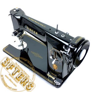 Puede incluir: M&aacute;quina de coser Singer vintage en negro brillante con detalles dorados. La m&aacute;quina presenta el logotipo de Singer y adornos dorados decorativos. El texto "THE SINGER MANUFACTURING CO." es visible. Un ejemplo cl&aacute;sico de artesan&iacute;a vintage.