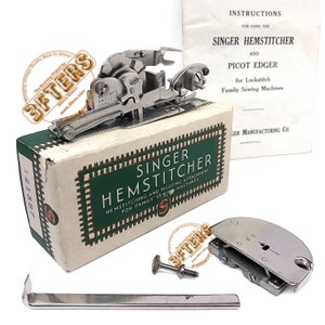 Könnte beinhalten: Ein Vintage Singer Hemmstich- und Zackenrand-Anbauteil für Familien-Nähmaschinen in seiner Originalverpackung. Die Schachtel ist weiß mit grünen Akzenten und dem aufgedruckten Text "Singer Hemmstich". Das Anbauteil ist aus Metall und hat eine silberne Oberfläche.