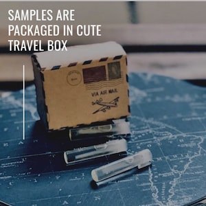 Puede incluir: Una peque&ntilde;a caja de cart&oacute;n marr&oacute;n con una tapa blanca, etiquetada como "VIA AIR MAIL" y el texto "SAMPLES ARE PACKAGED IN CUTE TRAVEL BOX." La caja est&aacute; encima de varios viales peque&ntilde;os y transparentes con tapas blancas, sobre un mapa azul.
