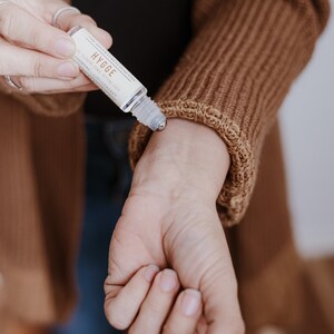 Puede incluir: Un frasco de vidrio transparente con una bola de rodillo de metal. El frasco est&aacute; etiquetado con "THE AGNES & GRAY CO. HYGGE RELAXING SKIN SCENTING OIL AROMATHERAPY & LINGONBERRY"