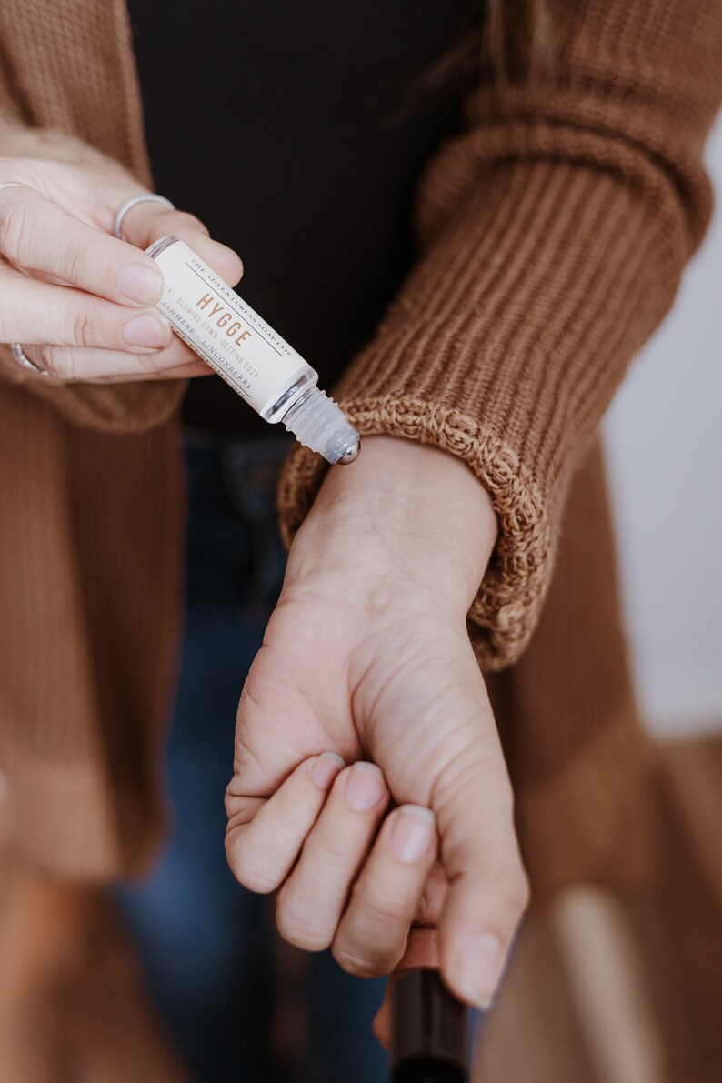 Puede incluir: Un frasco de vidrio transparente con una bola de rodillo de metal. El frasco est&aacute; etiquetado con "THE AGNES & GRAY CO. HYGGE RELAXING SKIN SCENTING OIL AROMATHERAPY & LINGONBERRY"