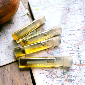 Puede incluir: Cuatro viales cil&iacute;ndricos transparentes llenos de un l&iacute;quido dorado est&aacute;n colocados sobre un mapa. Los viales tienen una tapa transparente y un peque&ntilde;o detalle en forma de burbuja. El mapa es una representaci&oacute;n colorida y detallada de un &aacute;rea geogr&aacute;fica.