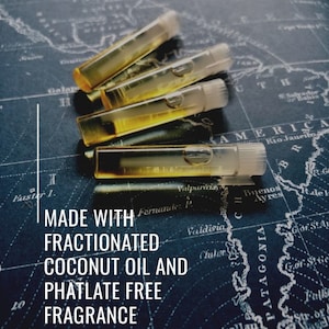 Puede incluir: Cuatro viales transparentes llenos de un l&iacute;quido dorado est&aacute;n dispuestos sobre un mapa. Los viales est&aacute;n etiquetados "MADE WITH FRACTIONATED COCONUT OIL AND PHATALATE FREE FRAGRANCE". El fondo es un mapa azul oscuro con texto blanco.