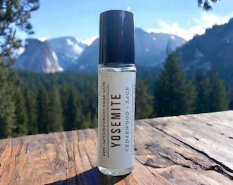 Pode incluir: Um frasco transparente de vidro com uma tampa preta. O frasco é rotulado com "THE ADVENTURESS SOAP CO® YOSEMITE CEDARWOOD + SAGE".