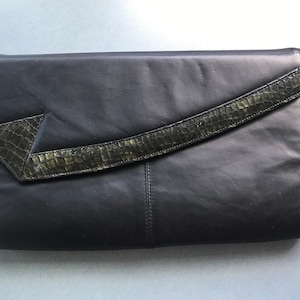May include: A black leather clutch with a green snakeskin flap.