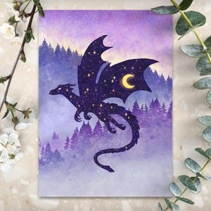 May include: A fantasy art print featuring a silhouette of a dragon with a starry body and a crescent moon on its wing. The dragon is set against a watercolor background of a forest and a purple and yellow sky.