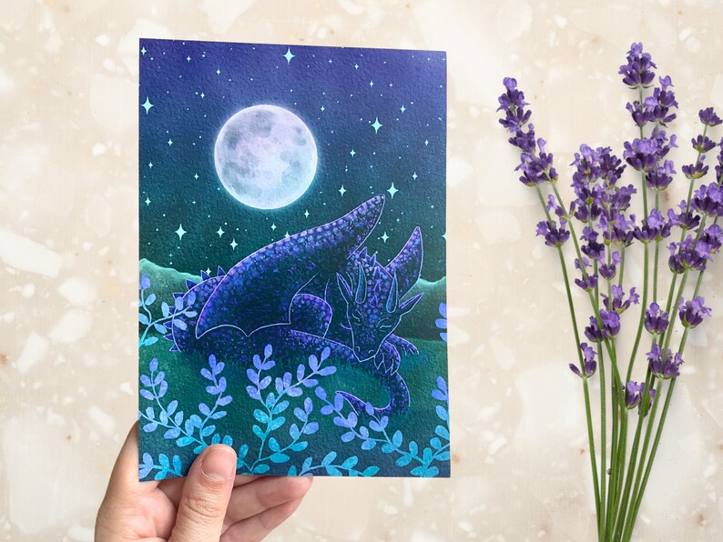 May include: A watercolor painting of a purple dragon sleeping under a full moon in a field of blue and green foliage.