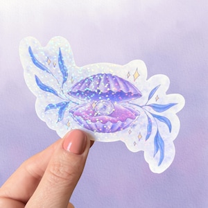 May include: A holographic sticker featuring a purple seashell with a white pearl inside, surrounded by blue leafy branches and small yellow star accents. The sticker has a die-cut shape with a shimmering, iridescent finish that reflects light.