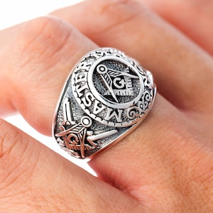 Könnte beinhalten: Ein silberner Freimaurer-Ring mit einem detaillierten Design, das einen Zirkel und ein Geodreieck, ein 'G' und die Worte 'Master Mason' zeigt.