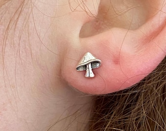 May include: A close-up of a silver mushroom-shaped earring. The earring is worn in the left earlobe.