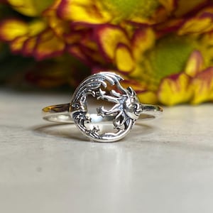 May include: A silver ring with a sun and moon design. The sun has a face and the moon has stars around it.