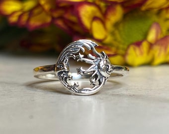 May include: A silver ring with a sun and moon design. The sun has a face and the moon has stars around it.