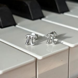 May include: A pair of silver earrings shaped like the mathematical symbol pi.