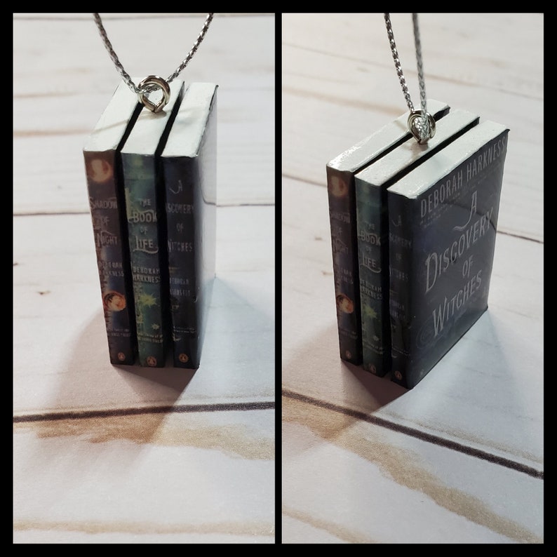May include: A silver chain necklace with a charm of three miniature hardcover books. The books are titled "Shadow of Night", "The Book of Life", and "A Discovery of Witches".