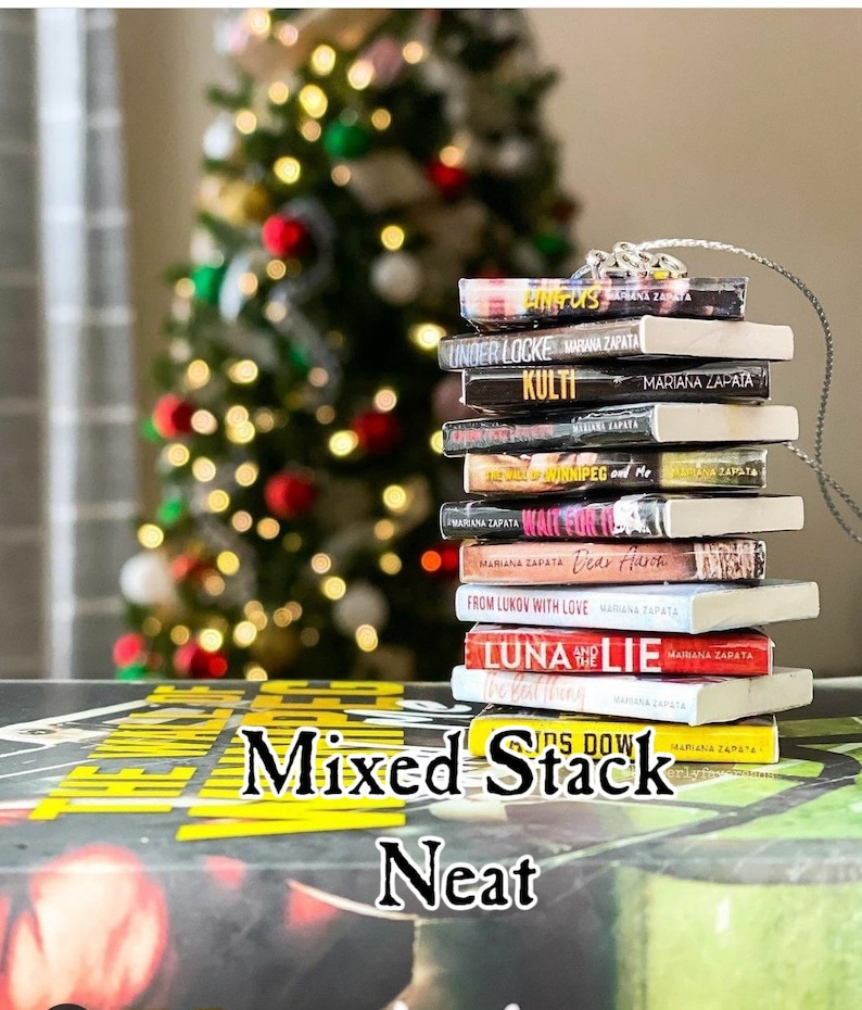 May include: A stack of miniature books with colorful covers, arranged neatly on a brown surface. The books are titled "Angus", "Under Locke", "Kulti", "The Wall of Winnipeg and Me", "Wait for It", "Dear Aaron", "From Lukov with Love", "Luna and the Lie", "Kids Don't Lie", and "The Last Mrs. Parrish". The text "Mixed Stack Neat" is printed on the surface below the books.