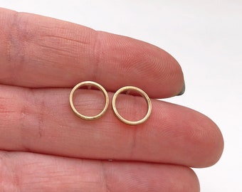 Puede incluir: Un par de pendientes de botón circulares de color dorado. Los pendientes son pequeños y delicados, y son perfectos para el uso diario.