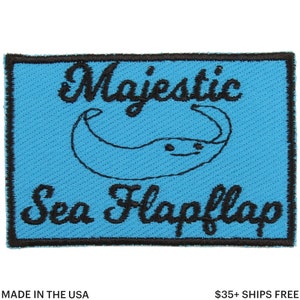 Peut inclure: Écusson rectangulaire avec un fond bleu clair et une bordure noire. L'écusson présente les mots "Majestic Sea Flapflap" en écriture noire, ainsi qu'une illustration de raie manta.