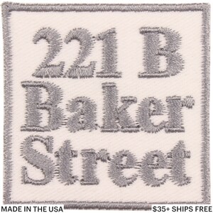 May include: Square, off-white patch with gray embroidered text. The text reads "221 B Baker Street". The patch has a gray border and the words "MADE IN THE USA" are at the bottom.