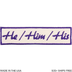 Könnte beinhalten: Ein rechteckiger Aufnäher mit cremefarbenem Hintergrund und lila Umrandung. Der Aufnäher zeigt den Text "He / Him / His" in einer handschriftlichen lila Schriftart. Die Wörter sind horizontal zentriert.