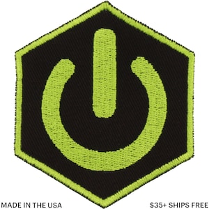 May include: A black, hexagonal patch with a neon green power button symbol. The patch has a neon green border and the text "MADE IN THE USA" at the bottom.