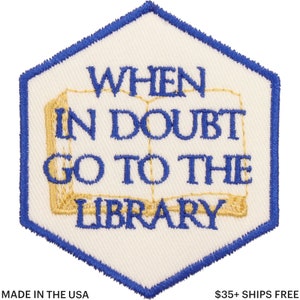 May include: Embroidered patch with a white background and a blue hexagonal border. The patch features the text "WHEN IN DOUBT GO TO THE LIBRARY" in blue, with a gold-colored book illustration. The phrase "MADE IN THE USA" is at the bottom.