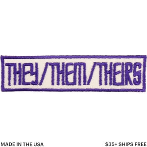May include: A rectangular patch with the text "THEY/THEM/THEIRS" embroidered in purple on a white background. The patch is bordered by a purple stitched outline. The words are in a bold, sans-serif font. The patch is made in the USA.