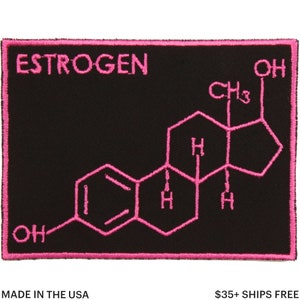 May include: Black rectangular patch with pink embroidered text and a molecular structure. The word "ESTROGEN" is at the top. The patch has a pink border and the text "MADE IN THE USA" at the bottom.