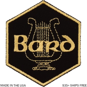Könnte beinhalten: Schwarz-goldener gestickter Aufnäher mit dem Wort "Bard" und einem Leier-Design. Der Aufnäher hat eine sechseckige Form mit einem goldenen Rand. Der Text "MADE IN THE USA" steht unten.