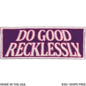 May include: A rectangular purple patch with the words "DO GOOD RECKLESSLY" embroidered in white with a pink outline. The patch has a white border and the text "MADE IN THE USA" at the bottom.