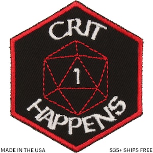 May include: Black, hexagonal patch with a red border. The patch features the words "CRIT HAPPENS" in white, surrounding a red, stitched D20 die with the number 1. The text "MADE IN THE USA" is at the bottom.