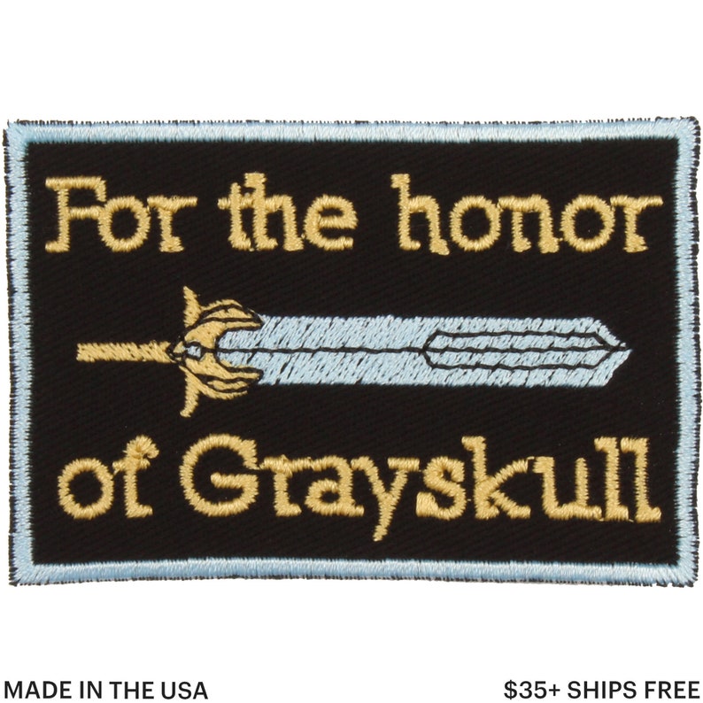 May include: Black rectangular patch with light blue border, featuring the text "For the honor of Grayskull" in gold lettering. A light blue sword with gold hilt is centered on the patch. Made in the USA.