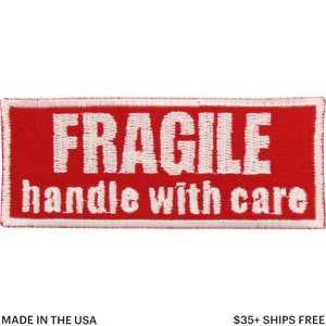 May include: A red rectangular patch with white embroidered text reading "FRAGILE handle with care." The patch has a white border, designed for application on packaging. The text "MADE IN THE USA" is at the bottom.