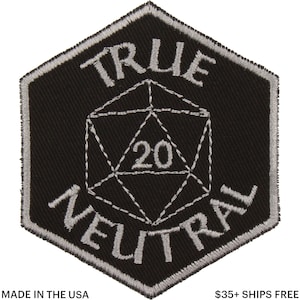 Puede incluir: Parche bordado en blanco y negro con el texto "TRUE NEUTRAL" que rodea un dado blanco de 20 caras. El parche es un hexágono negro con un borde plateado. El texto "MADE IN THE USA" está en la parte inferior.